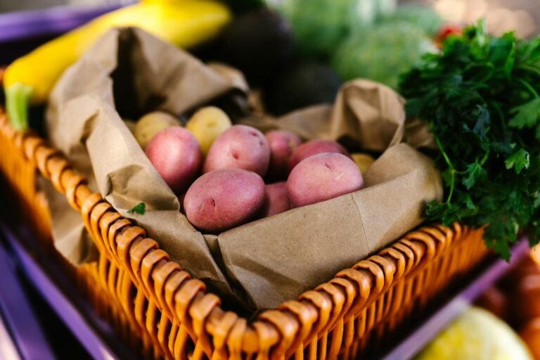 Assorted fresh vegetables including potatoes and parsley in a basket.